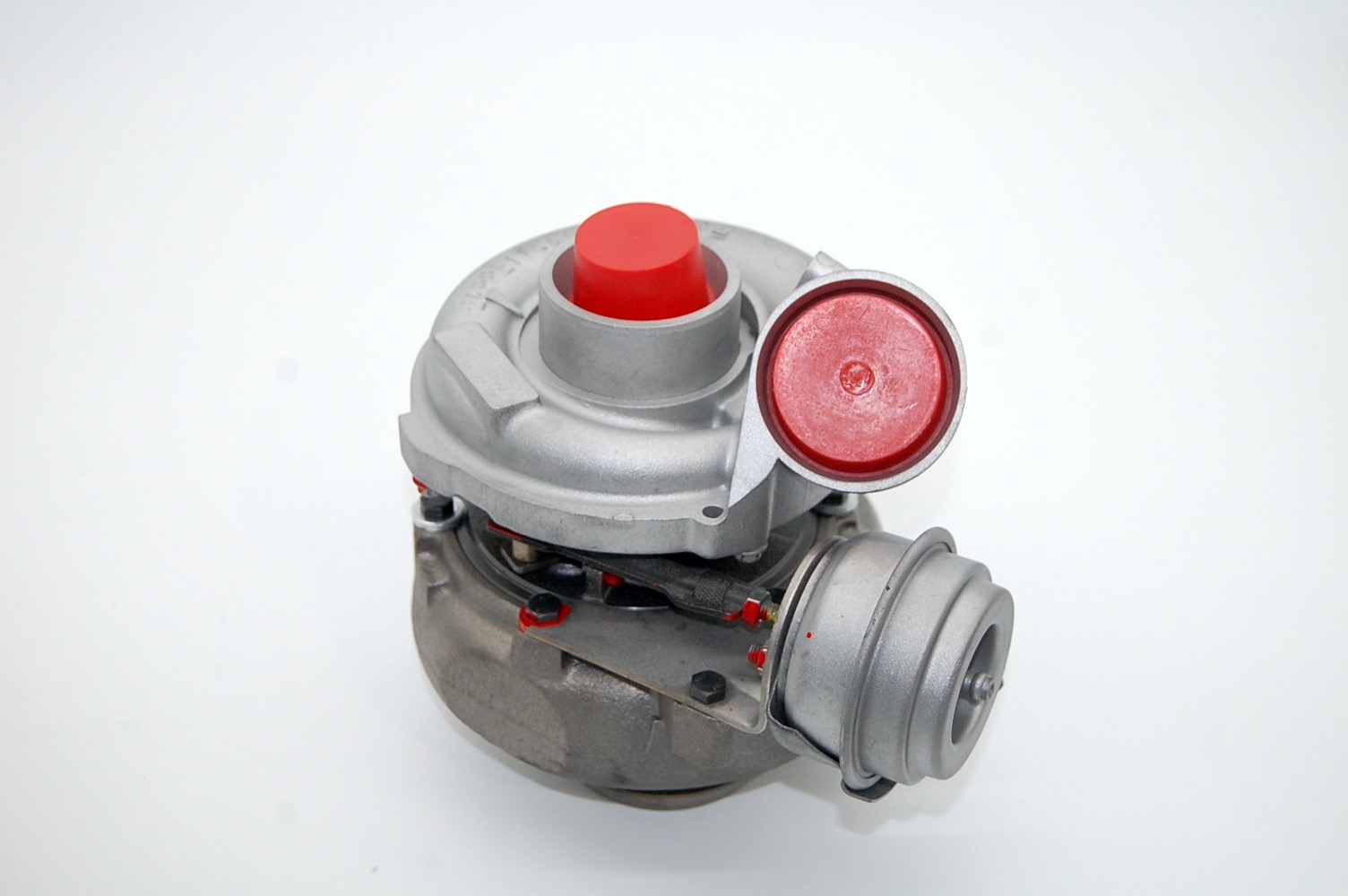Turbosprężarka samochodowa, zabezpieczona czerwonymi zaślepkami, na białym tle.
