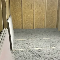 Poddasze w trakcie ocieplania: widoczne krokwie, płyty gipsowo-kartonowe oraz warstwa izolacji z wełny mineralnej.