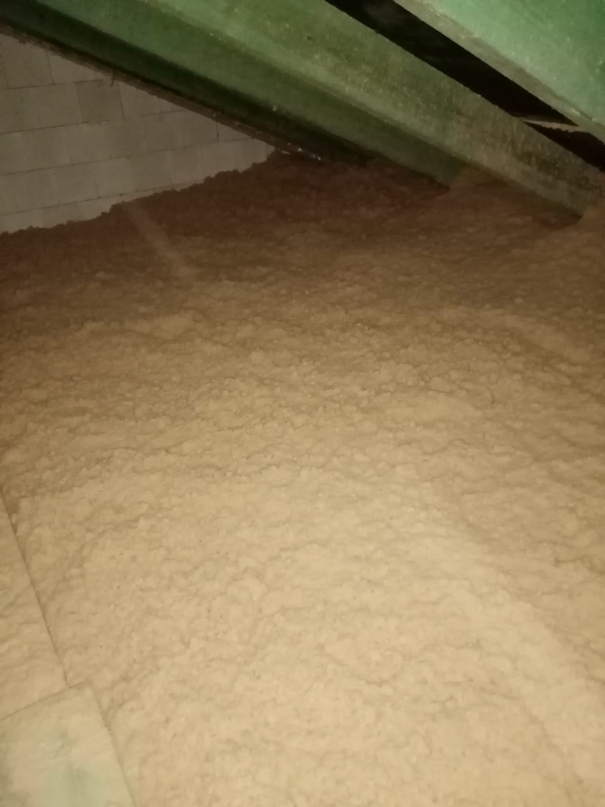 Poddasze po termoizolacji wdmuchiwanej wełną drzewną, widoczna warstwa izolacji pokrywająca powierzchnię, z fragmentem konstrukcji dachu w górnej części kadru.