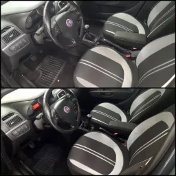 Wnętrze samochodu Fiat Punto z czarno-szarymi pokrowcami na siedzeniach z białymi paskami, widoczne deska rozdzielcza, kierownica z logo Fiat, dźwignia zmiany biegów i dywaniki.