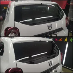 Biały samochód Dacia Duster z przyciemnionymi szybami z tyłu, widoczne światła, wycieraczka i logo marki, na czarnym tle z kolorowymi gwiazdkami.