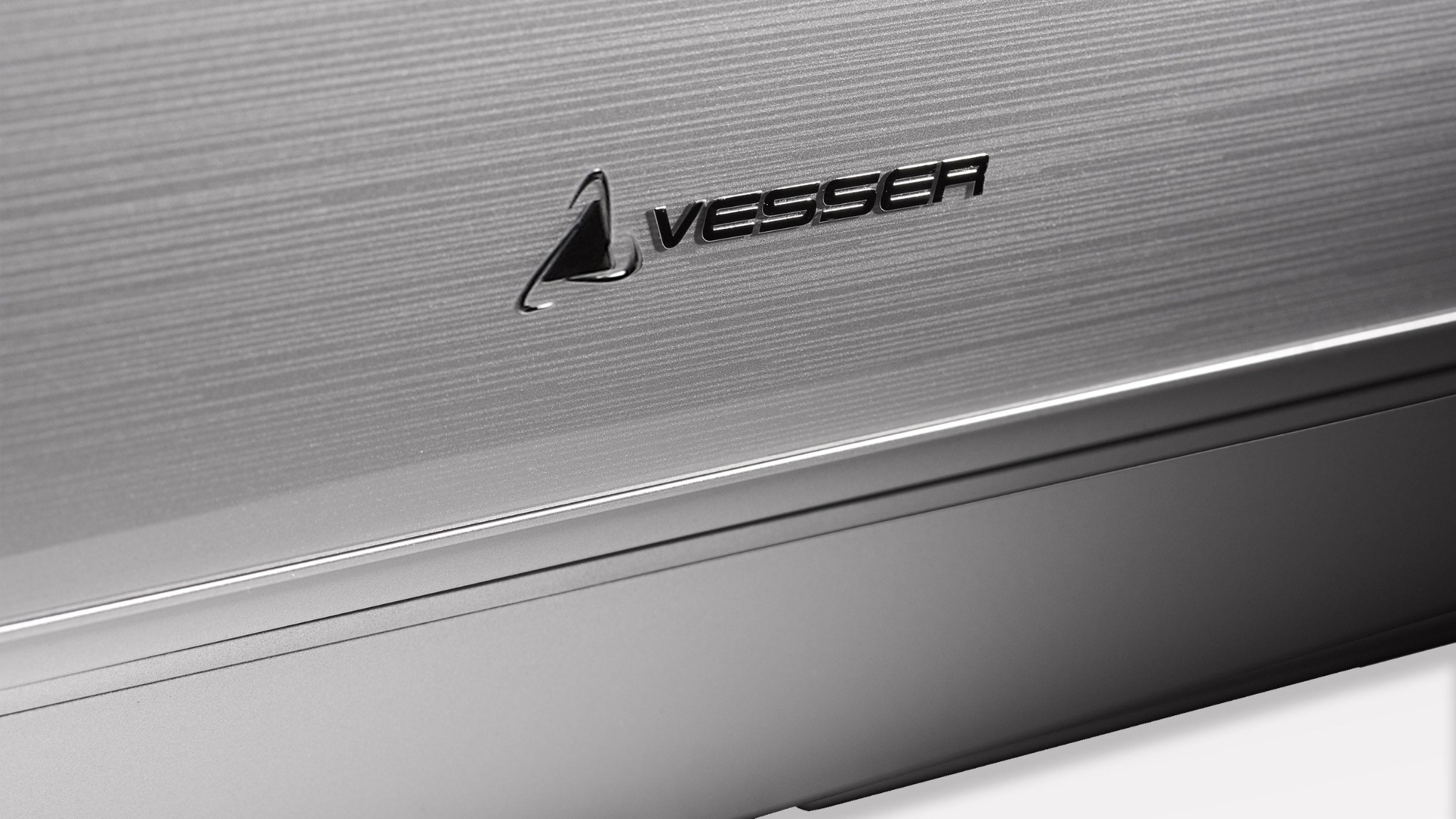 Szczegół klimatyzatora Vesser z metaliczną, szczotkowaną obudową i wyraźnym logo marki.