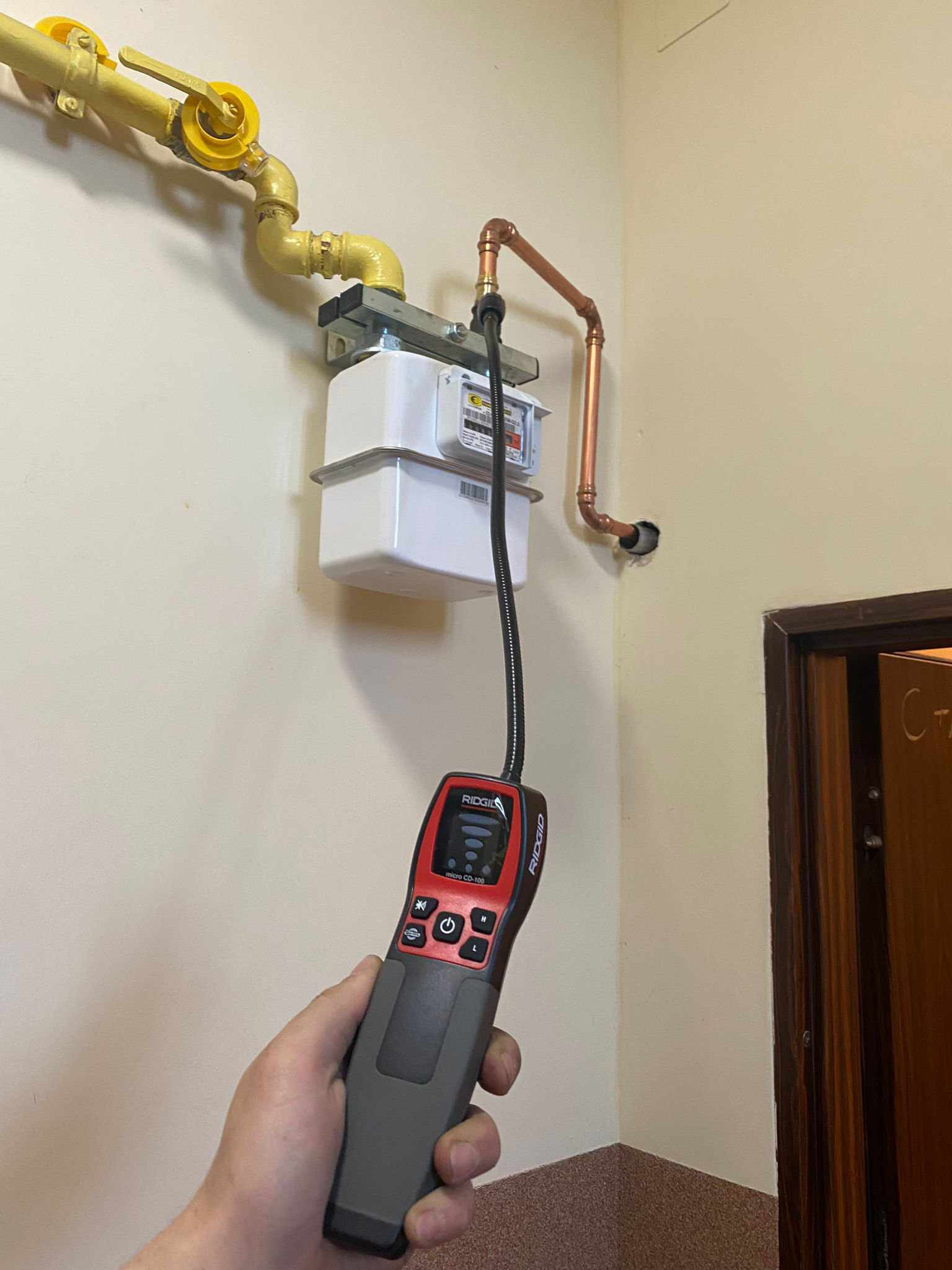 Pomiar nieszczelności instalacji gazowej przy użyciu detektora RIDGID micro CD-100, widoczny gazomierz i rury gazowe.