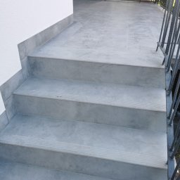 Paweł - Remonty i wykończenia - Schody zewnętrzne wyłożone szarymi płytkami gresowymi z antypoślizgowymi rowkami, prowadzące na taras z metalową balustradą.