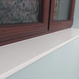 Faktoria Kamienia Grudzień Monika Juda - Biały parapet z konglomeratu pod oknem z brązową ramą, widok z dołu.