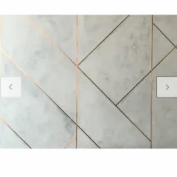 Dekoracyjna ściana z efektem betonu i geometrycznymi, miedzianymi liniami tworzącymi wzór.