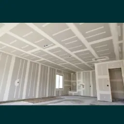 Wnętrze w trakcie wykańczania z zamontowanymi płytami kartonowo-gipsowymi na ścianach i suficie, widoczne profile i łączenia płyt.