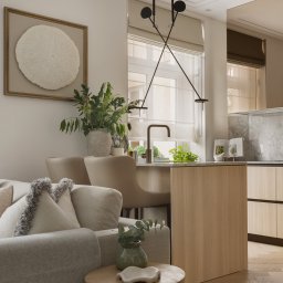 EMITOM design & build S.C. - Salon z widokiem na wyspę kuchenną z drewnianym frontem, minimalistyczna lampa wisząca, dekoracje roślinne i drewniana podłoga w jodełkę.