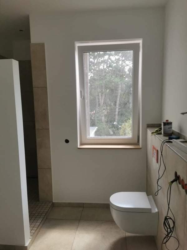 Montaż podwieszanej toalety w łazience w Stargardzie, widoczne płytki na ścianach i podłodze, okno z widokiem na drzewa, przygotowane instalacje elektryczne i sanitarne.