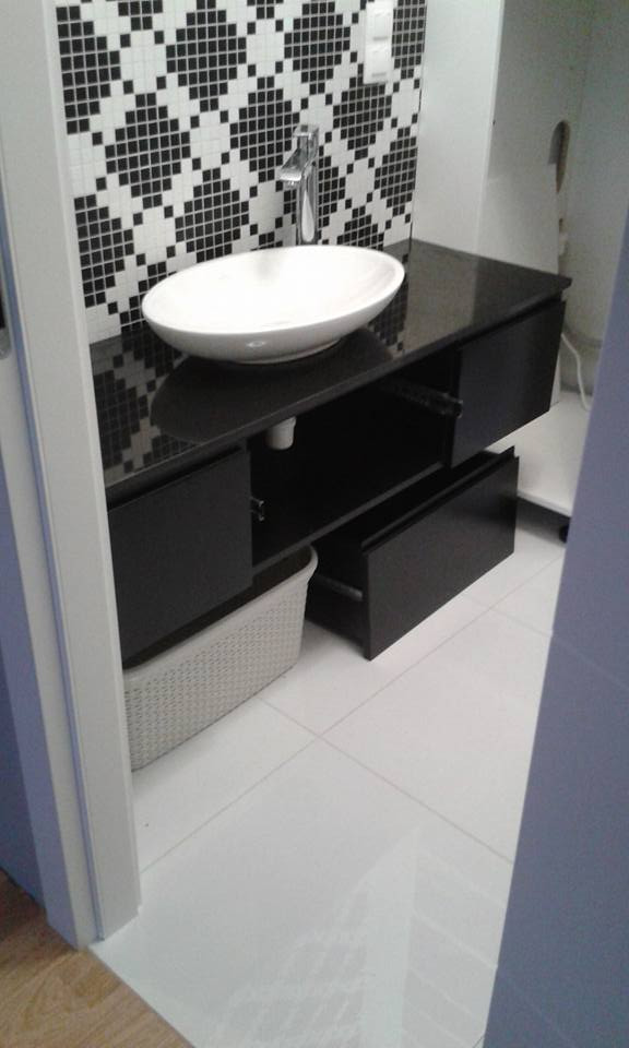 Nowoczesna łazienka: biała, owalna umywalka nablatowa na czarnym blacie z szufladami, białe płytki podłogowe, ściana z mozaiką w czarno-białą kratkę, bateria umywalkowa.