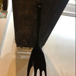 Rebus - Ciemnobrązowy, drewniany blat stołu przymocowany do ściany za pomocą metalowych wsporników i ozdobnej, drewnianej nogi w stylu retro z czterema smukłymi odnogami.