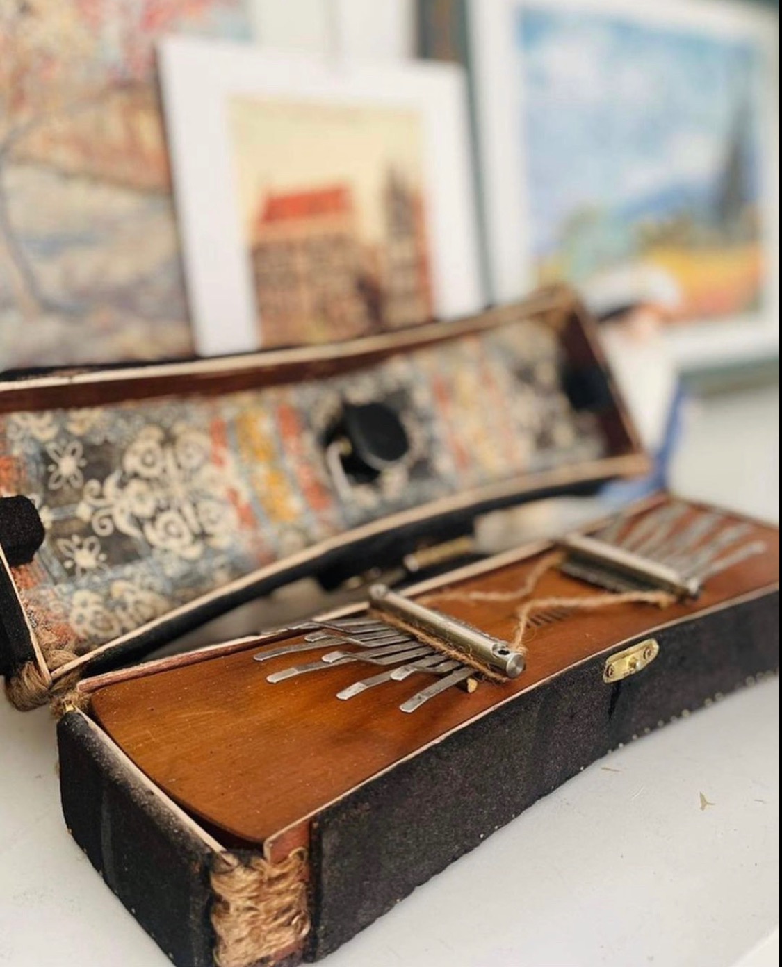 Otwarta, ręcznie robiona kalimba w pudełku z wyściółką w stylu vintage, na tle rozmytych obrazów.