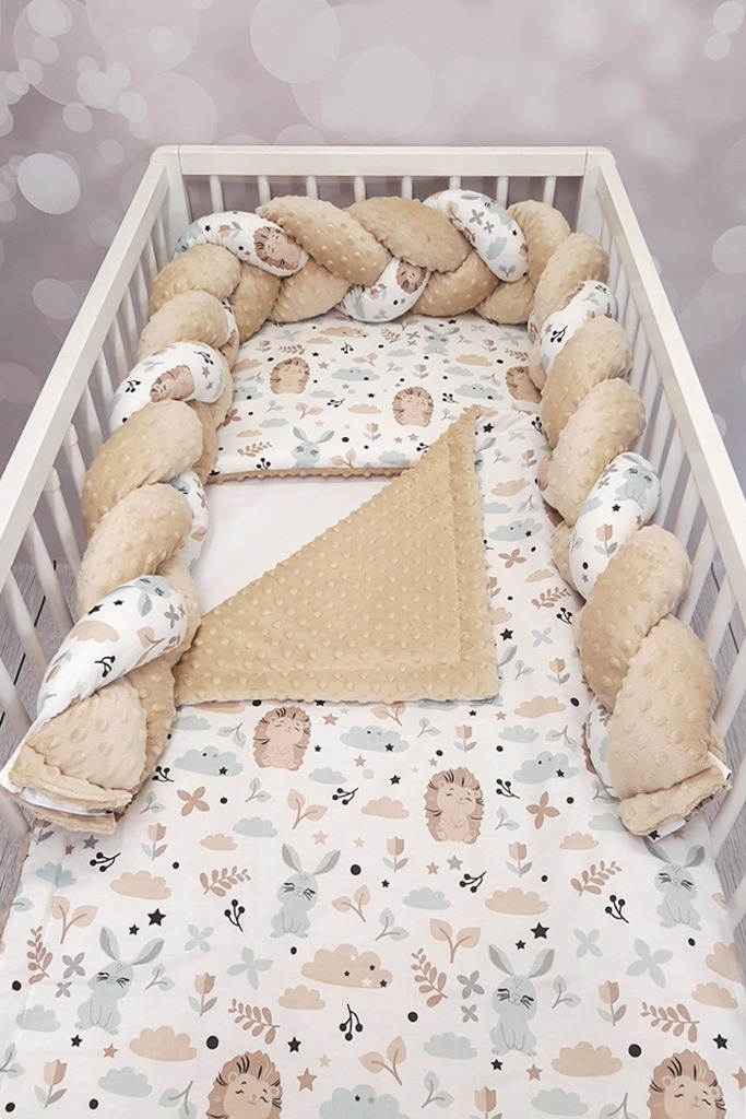 Dziecięce łóżeczko z kompletem pościeli: ochraniacz w formie plecionki, kołderka z fakturą w kropki i prześcieradło w króliczki i jeże.