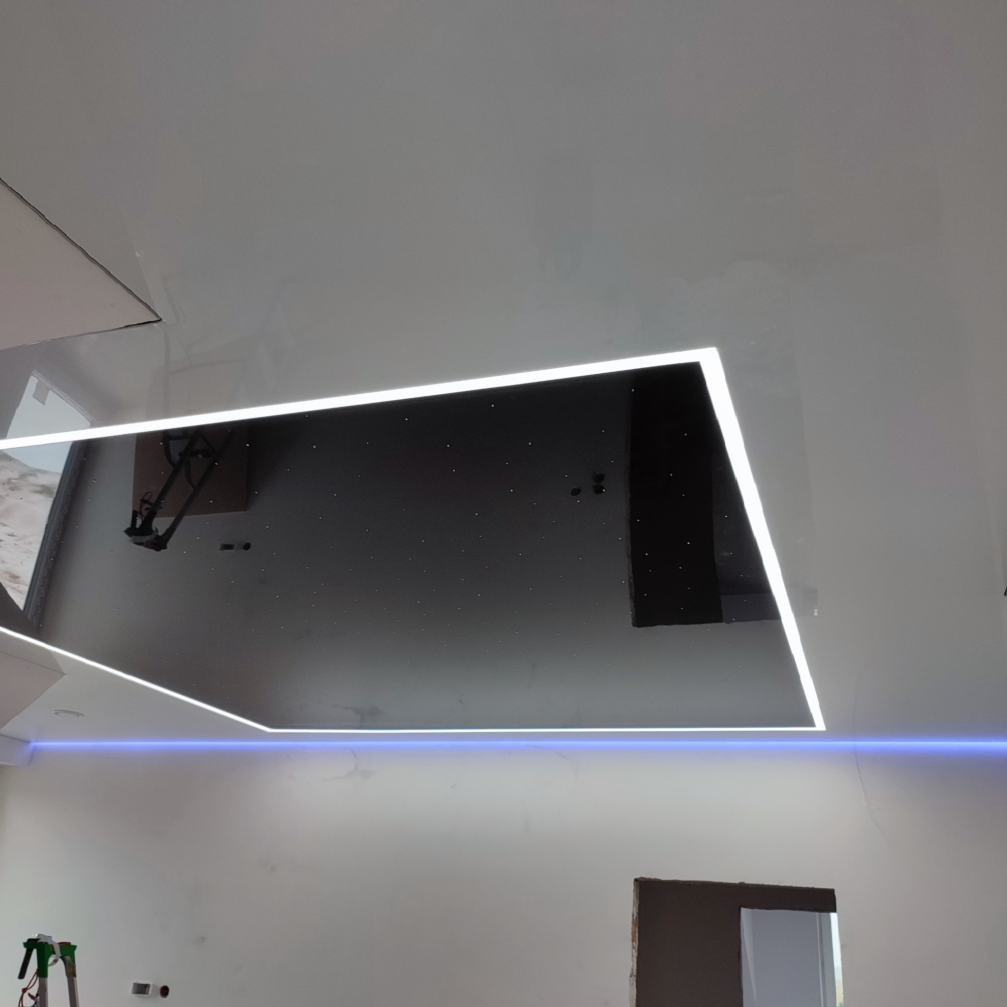 Sufit podwieszany z płyty karton gips z efektem gwieździstego nieba i oświetleniem LED, widoczne niedoskonałości na ścianie i drabina malarska.