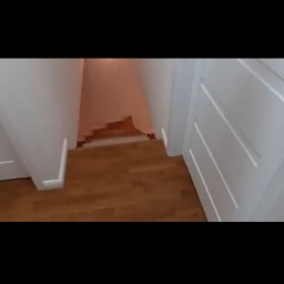 Kosmiczne Remonty - Widok z góry na drewniane schody w domu w Piasecznie, z białymi ścianami i listwami przypodłogowymi, prowadzące do pomieszczenia z pomalowaną ścianą na różowo.