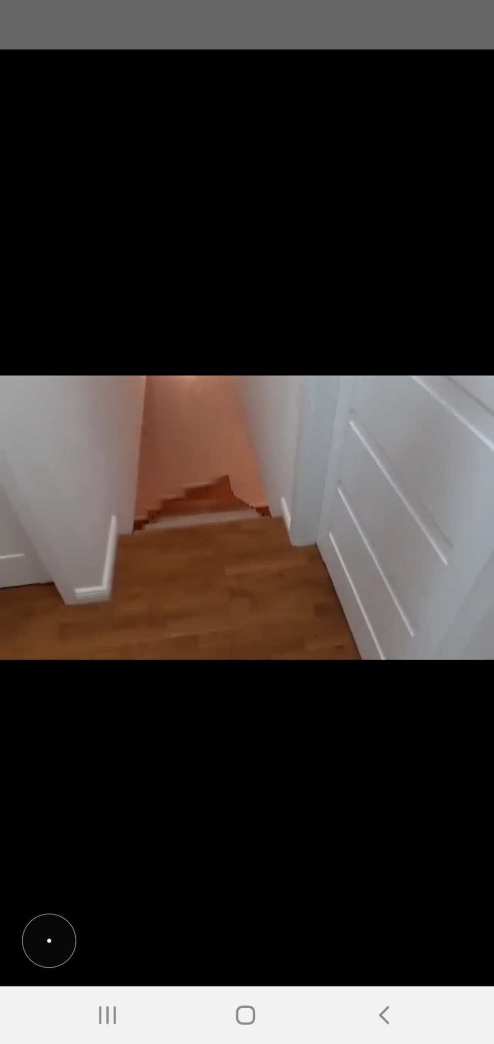 Widok z góry na drewniane schody w domu w Piasecznie, z białymi ścianami i listwami przypodłogowymi, prowadzące do pomieszczenia z pomalowaną ścianą na różowo.