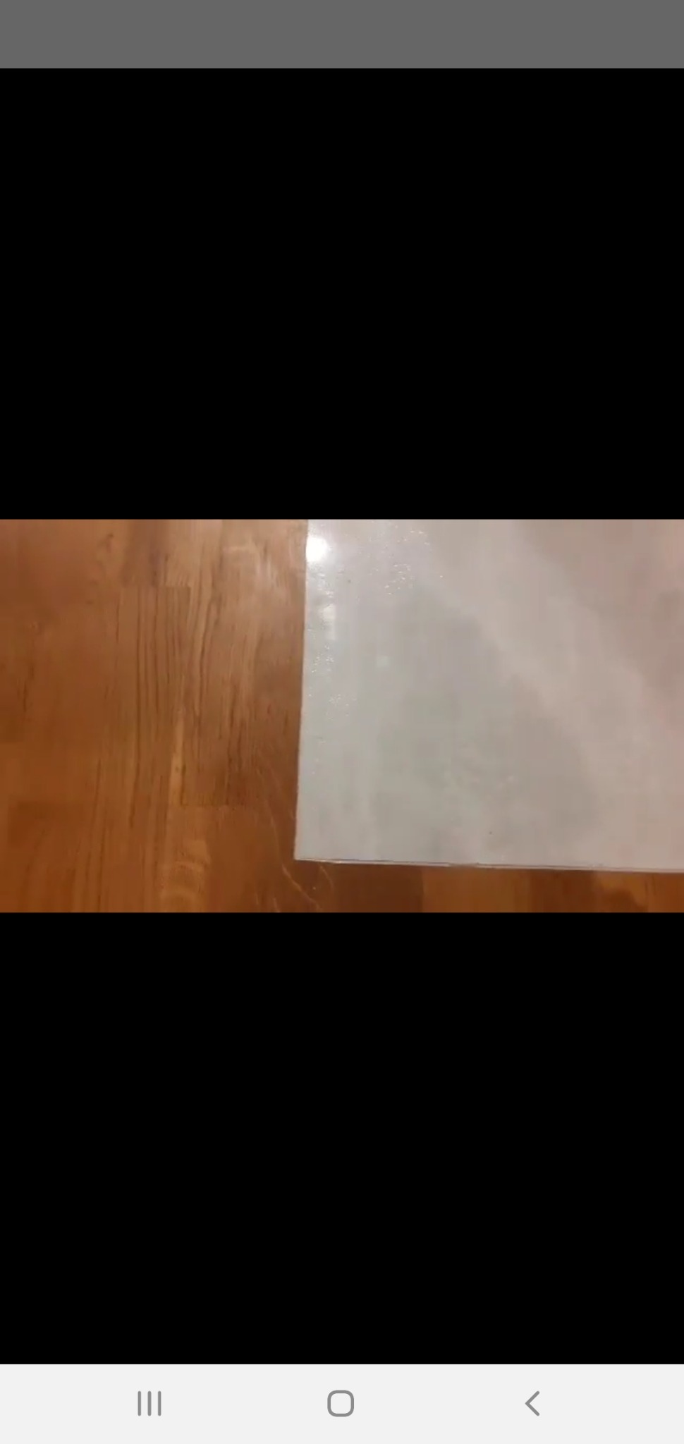 Fragment podłogi z drewnianymi panelami sąsiadujący z jasną, prawdopodobnie wykafelkowaną powierzchnią, widoczne niedoskonałości i nierówności na łączeniu materiałów.