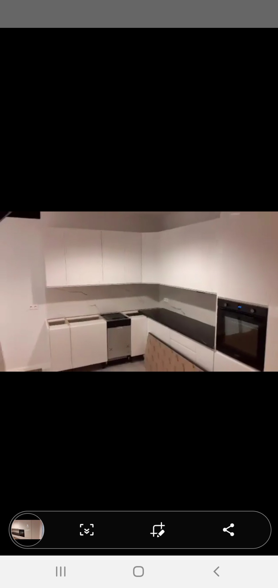 Wnętrze kuchni w trakcie montażu: białe szafki wiszące i stojące z ciemnym blatem, brakujące fronty dolnych szafek, karton na podłodze, zabudowany piekarnik.