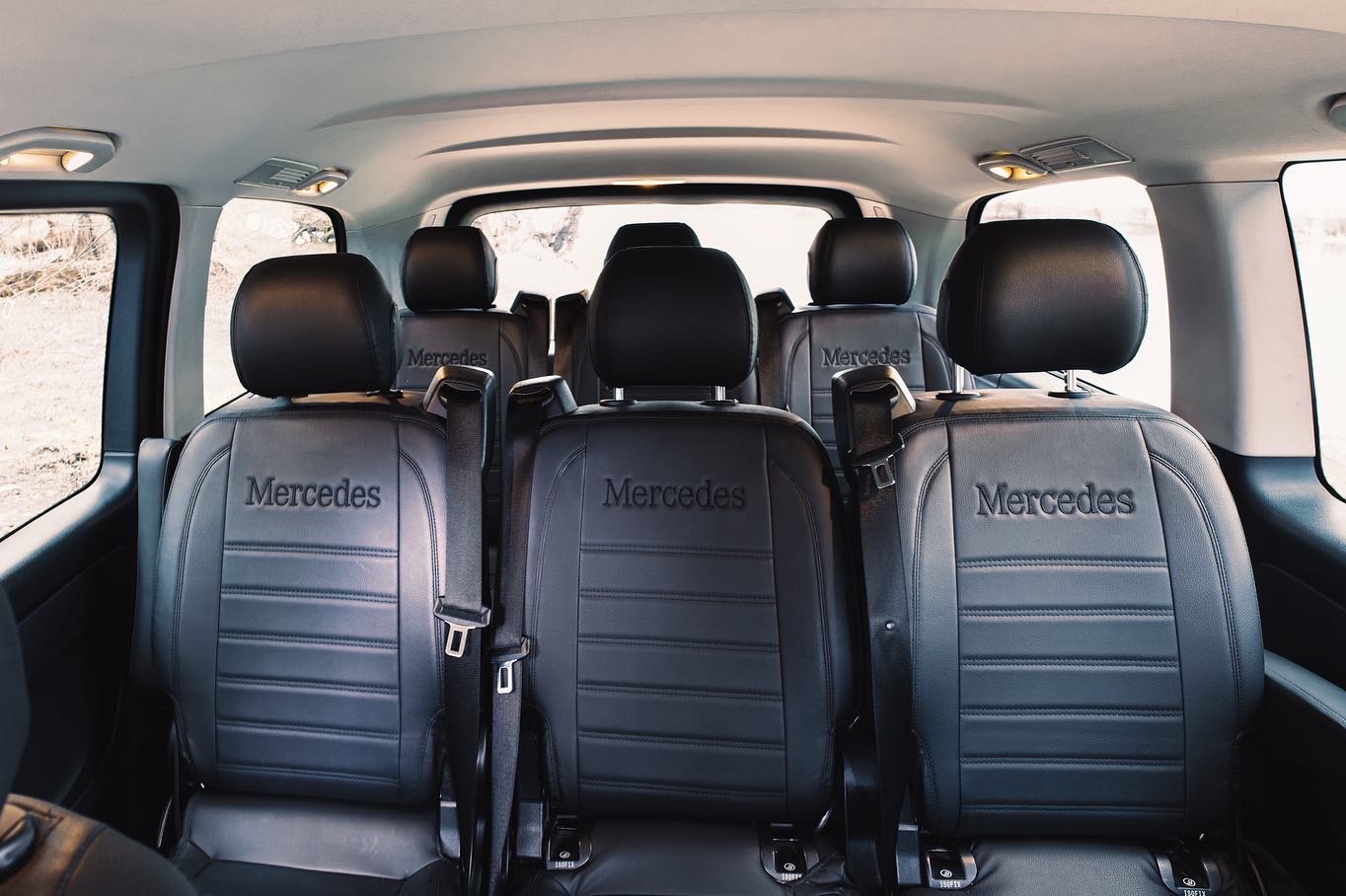 Wnętrze luksusowego busa z czarnymi skórzanymi fotelami z napisem Mercedes, widok z tyłu.