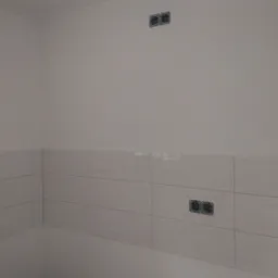 Białe płytki ścienne z widocznymi puszkami instalacyjnymi pod gniazdka elektryczne, surowy stan wykończenia wnętrza.