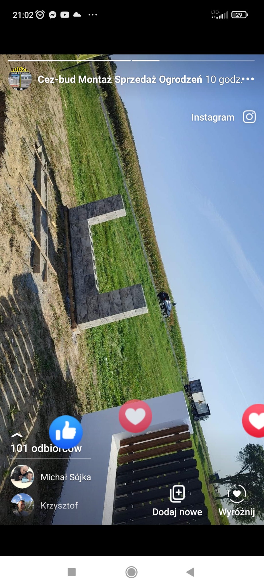 Wznoszenie fundamentów pod ogrodzenie z bloczków betonowych na tle pola kukurydzy, widoczne drewniane szalunki i częściowo ukończony fragment konstrukcji.