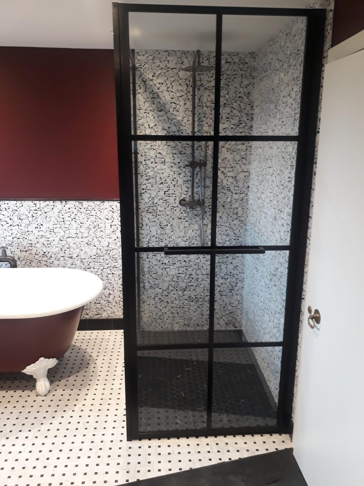 Nowoczesna łazienka z kabiną prysznicową w stylu loft z czarnymi szprosami, mozaiką na ścianach i podłodze, oraz wolnostojącą wanną na lwich nóżkach.