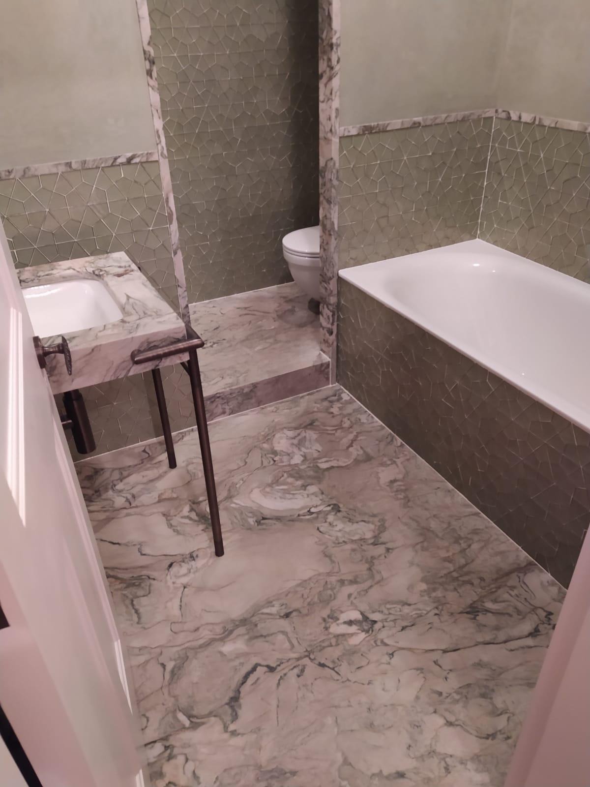 Nowoczesna łazienka z marmurową podłogą i umywalką na metalowym stelażu, mozaiką na ścianach i białą wanną.