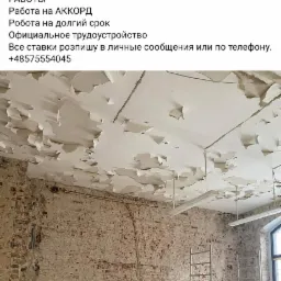 Pokój w trakcie remontu: zniszczony sufit z odpadającą farbą, odsłonięta ceglana ściana z widocznymi instalacjami, aluminiowy rusztowanie i gruz na podłodze.