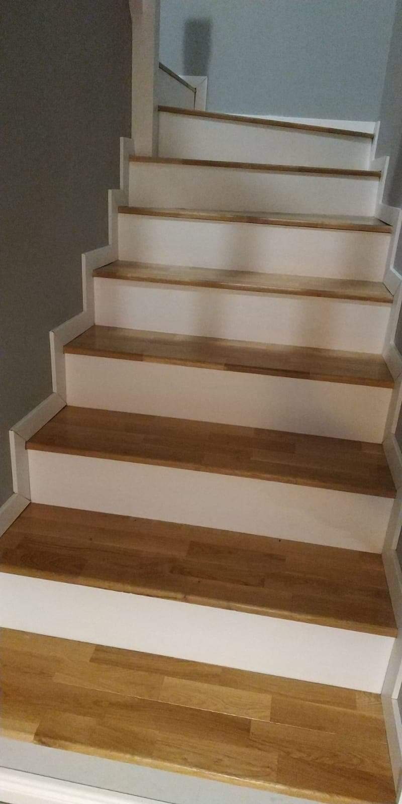 Odnowione schody z drewnianymi stopniami i białymi podstopnicami w domu w Barlinku. Widoczne świeżo pomalowane elementy.