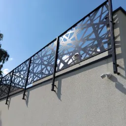 Nowoczesna, czarna balustrada z geometrycznym wzorem na balkonie, widoczna kamera monitoringu na elewacji budynku