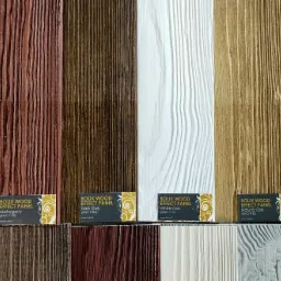 Prezentacja różnych wariantów paneli elewacyjnych Bolix Wood Effect Panel w odcieniach mahoniu, dębu ciemnego, dębu białego, dębu naturalnego i dębu złotego, z widocznymi etykietami produktowymi.