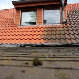 KOLORTEK - TOMASZ TWARDOSZ - Dachówkowy dach z oknem połaciowym, widoczna różnica między umytą a zabrudzoną częścią, zarys rynny na pierwszym planie.