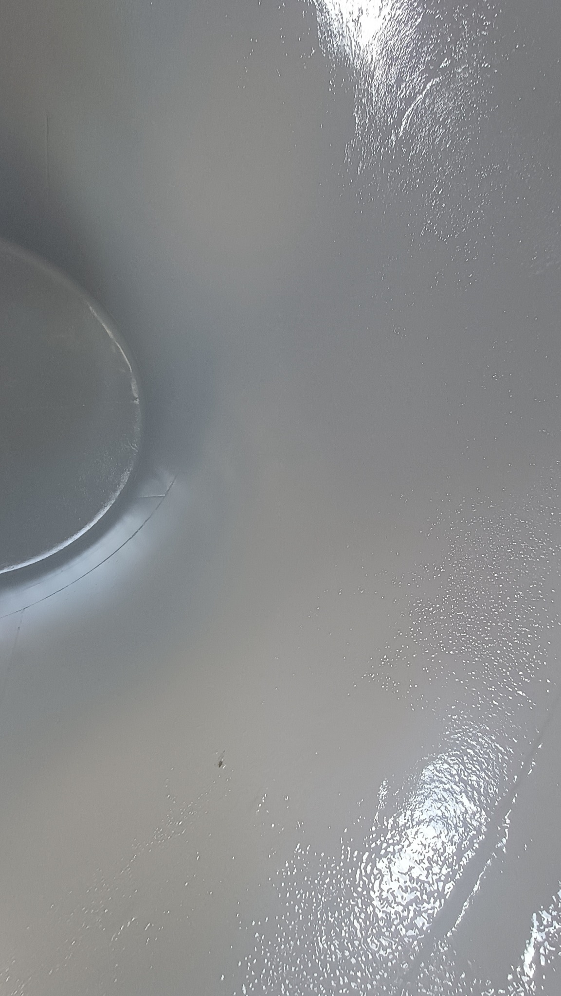 Świeżo pomalowany, błyszczący dach w Harbutowicach, z widocznym fragmentem rynny. Gładka, jednolita powierzchnia w odcieniach szarości, odbijająca światło.