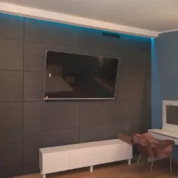 Szara ściana z podświetleniem LED, wiszący telewizor, biała szafka RTV i różowe krzesło na parkiecie.