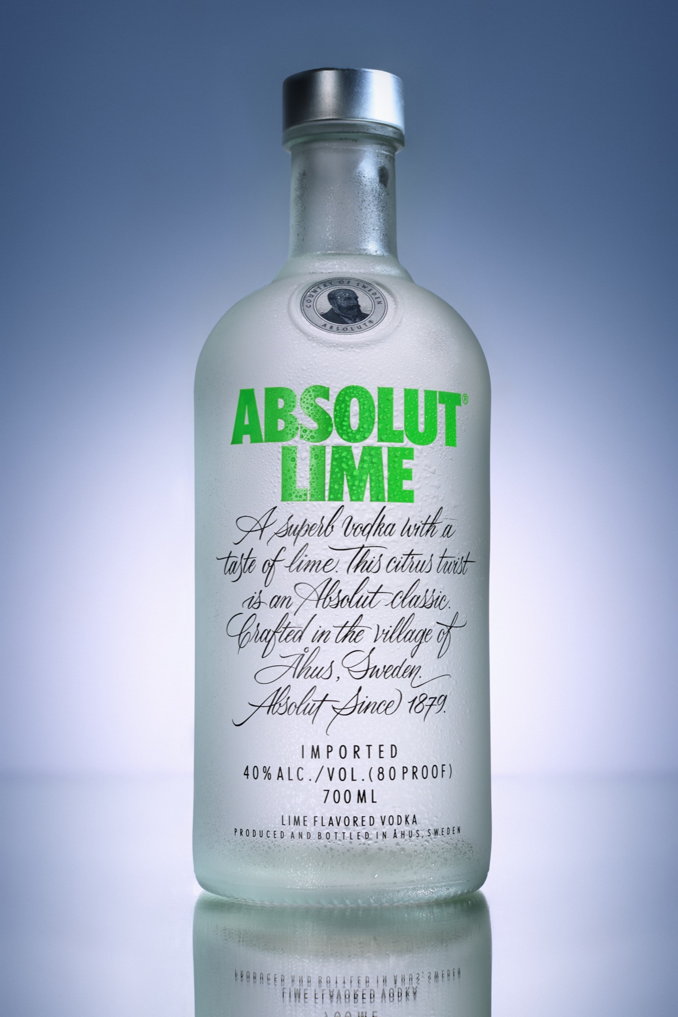 Butelka wódki Absolut Lime na jasnoniebieskim tle, pokryta kroplami, z widocznym odbiciem na błyszczącej powierzchni.