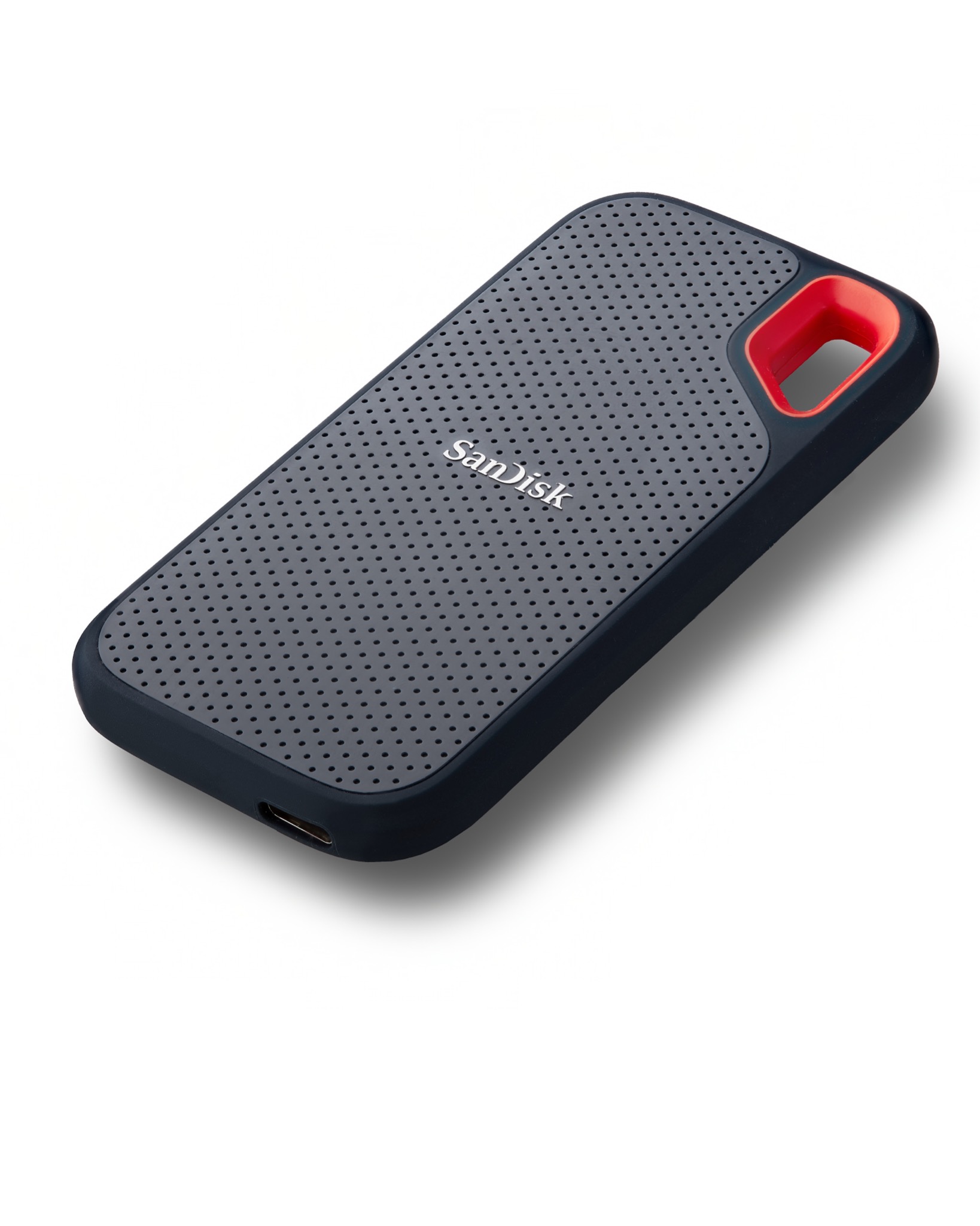 Szary dysk SSD SanDisk z perforowaną powierzchnią i czerwonym akcentem, leżący na białym tle.