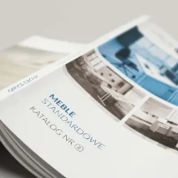 Otwarty katalog mebli biurowych z widocznymi zdjęciami aranżacji wnętrz biurowych w błękitnej tonacji.