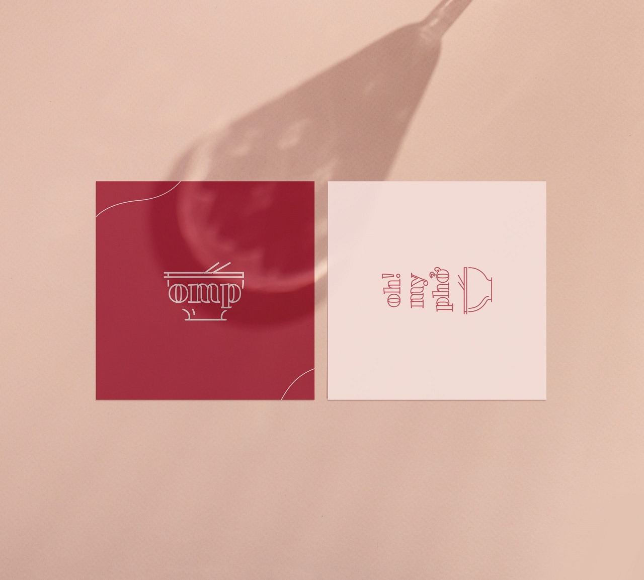 Dwie kwadratowe wizytówki z minimalistycznymi ilustracjami i napisami w odcieniach czerwieni i beżu, rzucające cień na gładkie, beżowe tło.