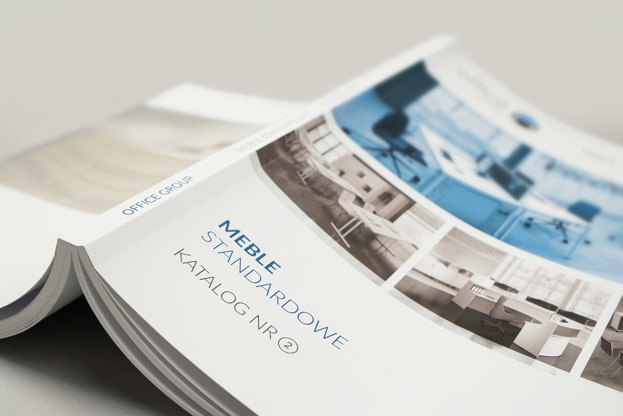Otwarty katalog mebli biurowych z widocznymi zdjęciami aranżacji wnętrz biurowych w błękitnej tonacji.