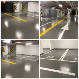 Wypolerowana, szara posadzka w garażu podziemnym z wyznaczonymi, białymi liniami miejsc parkingowych o numerach 33, 34, 55, 56, 59, 60 oraz żółtymi pasami dla osób niedowidzących i strzałką...