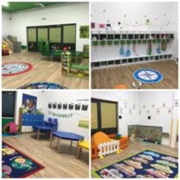 Wnętrze sali przedszkolnej: drewniana podłoga, kolorowe dywany z motywami dziecięcymi, niskie meble dostosowane do wzrostu dzieci, ściany zdobione edukacyjnymi dekoracjami i grafikami, w tle...