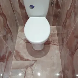 Biała toaleta z widocznym logo Cersanit, zamontowana w łazience wykończonej płytkami imitującymi marmur w odcieniach różu i brązu, z półką nad toaletą wyłożoną tymi samymi płytkami.