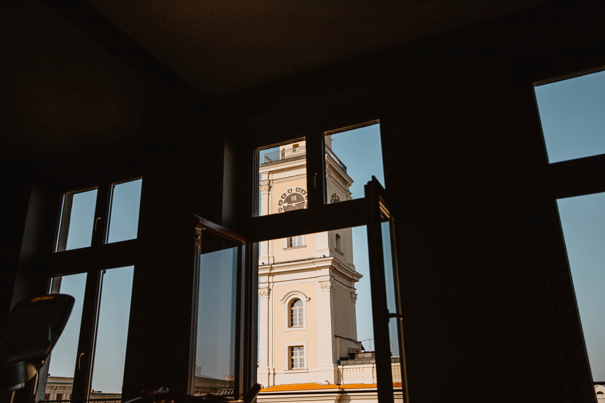 Widok z okna sali treningowej na wieżę zegarową w słoneczny dzień.