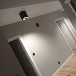 Kamil Maślanka Usługi Remontowo-Budowlane. New Life. - Szare ściany w korytarzu po remoncie, widoczne listwy przypodłogowe i oświetlenie punktowe. Ujęcie z dołu, podkreślające wysokość pomieszczenia.