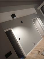 Szare ściany w korytarzu po remoncie, widoczne listwy przypodłogowe i oświetlenie punktowe. Ujęcie z dołu, podkreślające wysokość pomieszczenia.