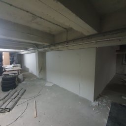 Usługi remontowe - Montaż ścian działowych z płyt karton gips w piwnicy, widoczne narzędzia i opony, surowy betonowy strop
