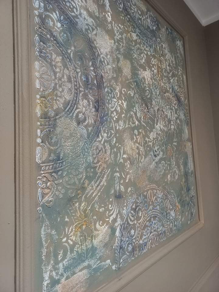 Fragment ściany z ozdobnym, teksturowanym malowaniem w odcieniach szarości, błękitu i złota, imitującym wzór tapety i ornamenty, obramowany listwą.