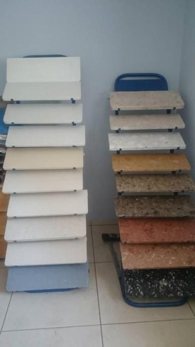 Ekspozycja próbek blatów i parapetów w różnych kolorach i wzorach, umieszczonych na metalowych stojakach.