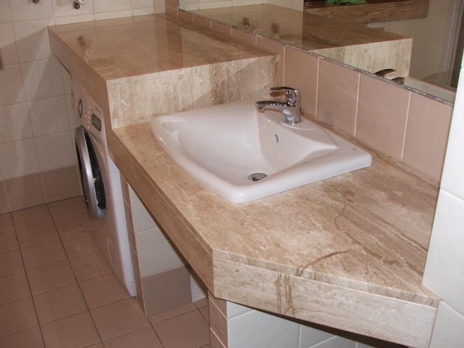 Beżowy blat z marmurkowym wzorem w łazience, z umywalką i baterią, obok pralka.