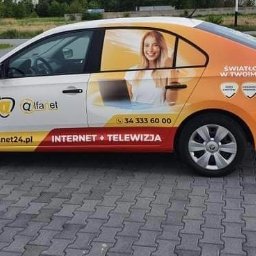 Skandruk Bis - Oklejony samochód firmy Alfanet24 z reklamą usług internetu i telewizji, z wizerunkiem kobiety korzystającej z laptopa.